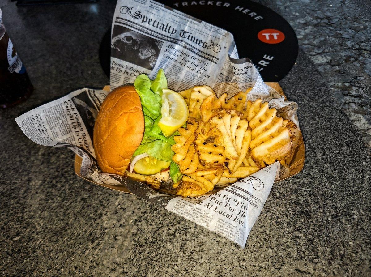 Grouper Shack grilled fish sandwich with lettuce, pickle, lemon and waffle fries in newspaper-lined basket, Jacksonville Beach