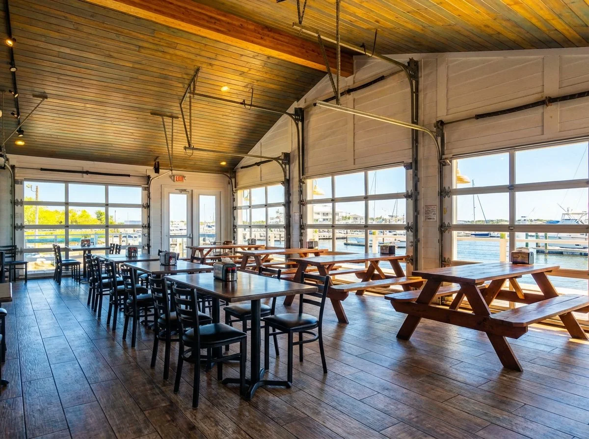 Dockside Seafood Restaurant interior with garage doors open to the marina and picnic tables