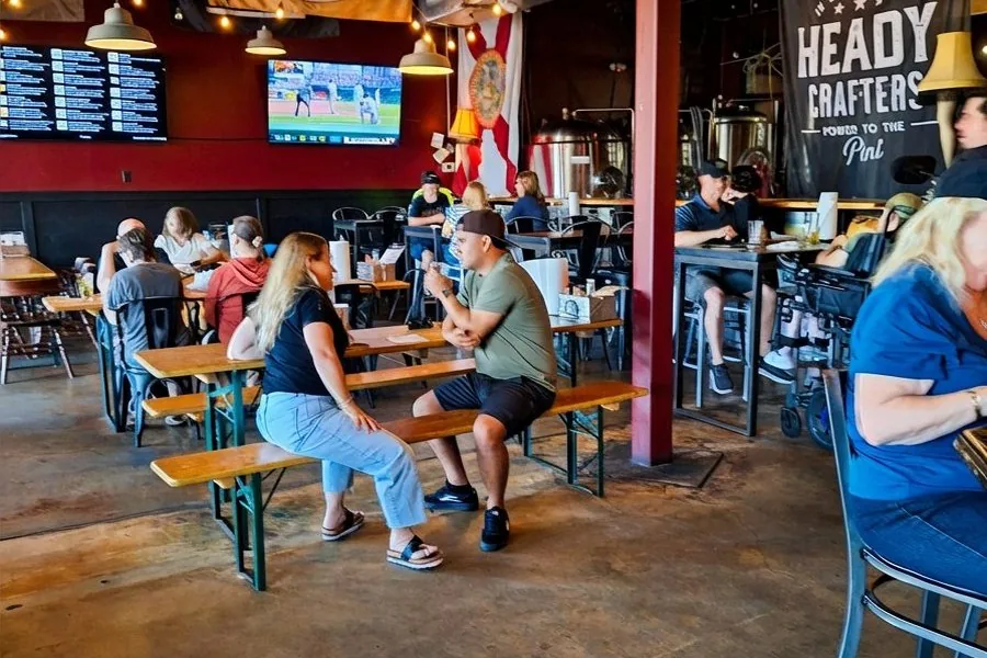 Engine 15 Brewing Co. taproom with guests at tables, craft beer flags and brewing equipment visible